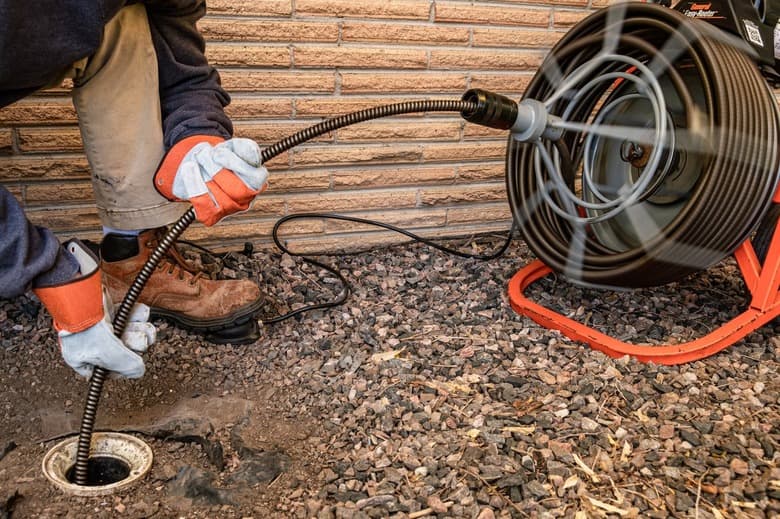 Plumber running a drain cable through an outdoor cleanout during professional drain cleaning in San Jacinto, CA